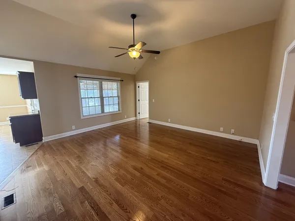 a view of an empty room with a window and wooden floor