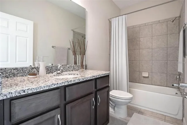 a bathroom with a granite countertop sink toilet mirror and bathtub