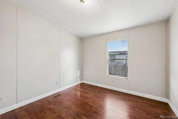 an empty room with wooden floor and window