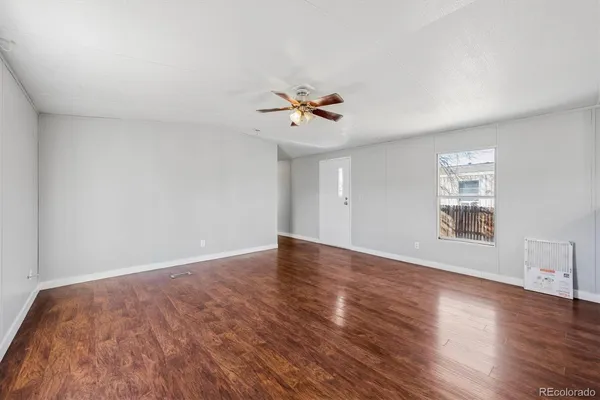 a view of a big room with wooden floor and a chandelier fan