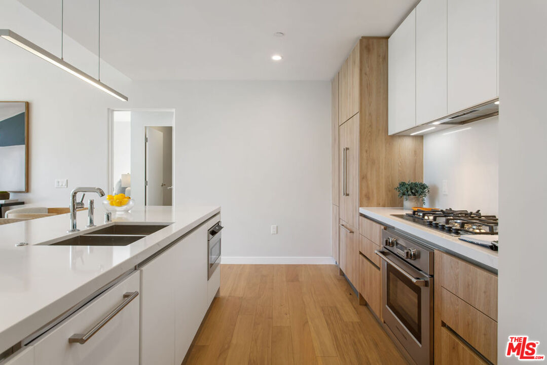 11600 Dunstan Way, Unit 404 Los Angeles, CA 90049 - Photo 13 of 28 a kitchen with stainless steel appliances a sink stove and cabinets