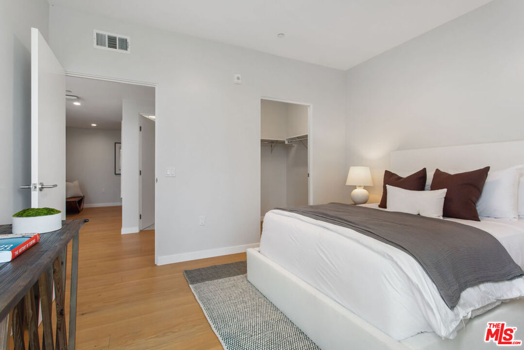 11600 Dunstan Way, Unit 404 Los Angeles, CA 90049 - Photo 23 of 28 a spacious bedroom with a bed and a lamp on a table