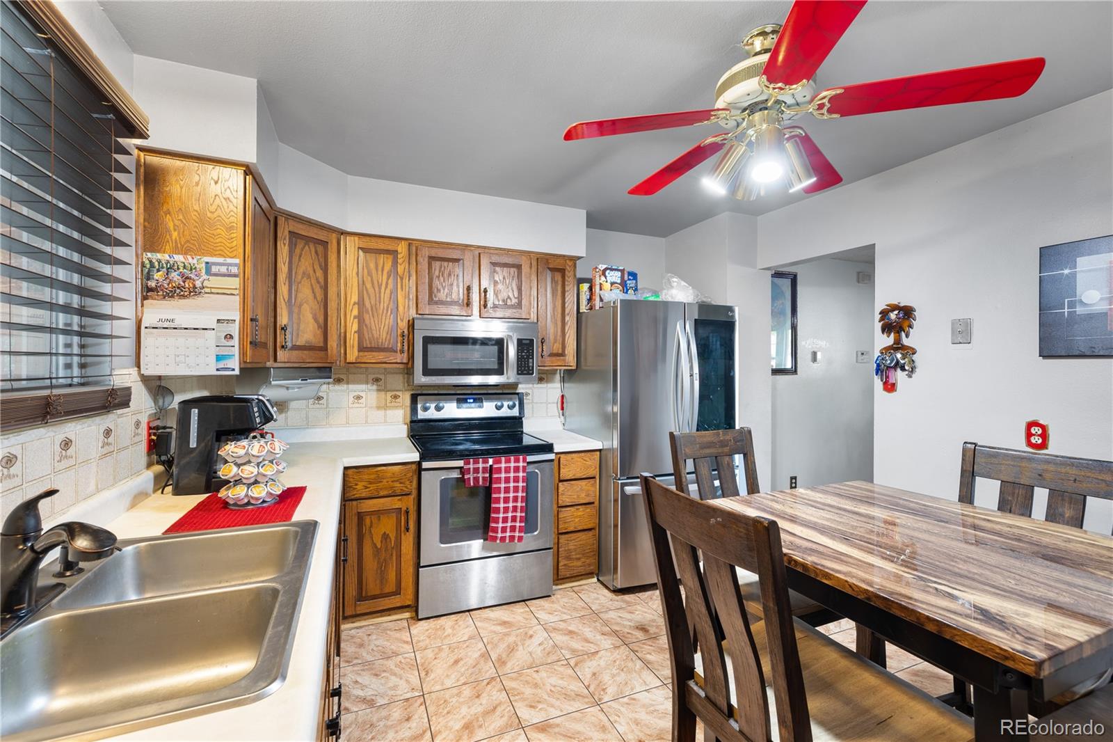 5311 Troy Street Denver, CO 80239 - Photo 12 of 46 a kitchen with stainless steel appliances kitchen island granite countertop a table chairs in it and a window