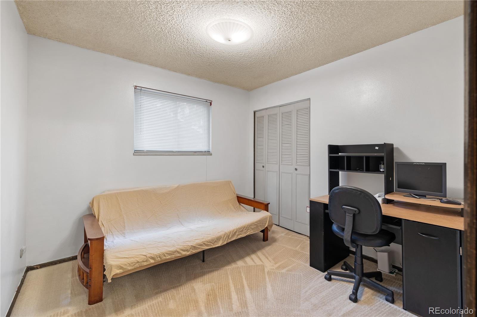5311 Troy Street Denver, CO 80239 - Photo 21 of 46 a bedroom with a bed and a workspace