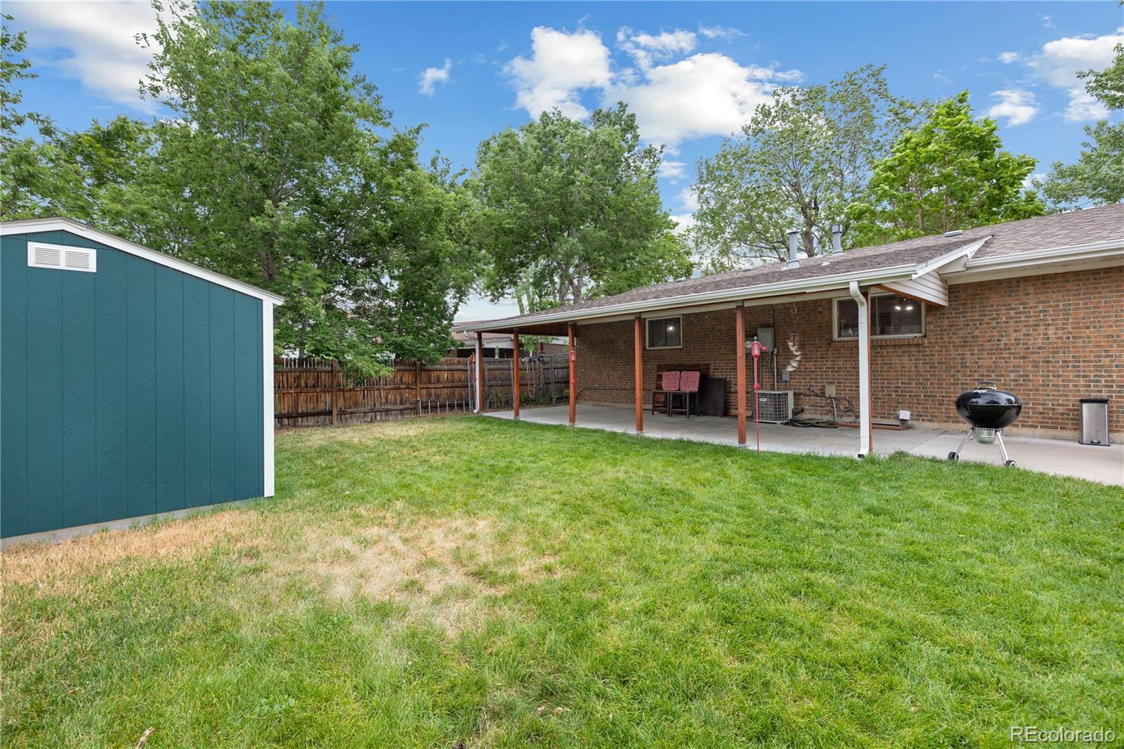 5311 Troy Street Denver, CO 80239 - Photo 45 of 46 a view of a backyard with table and chairs potted plants and large tree