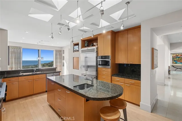 a kitchen with stainless steel appliances granite countertop a sink a stove and a wooden cabinets