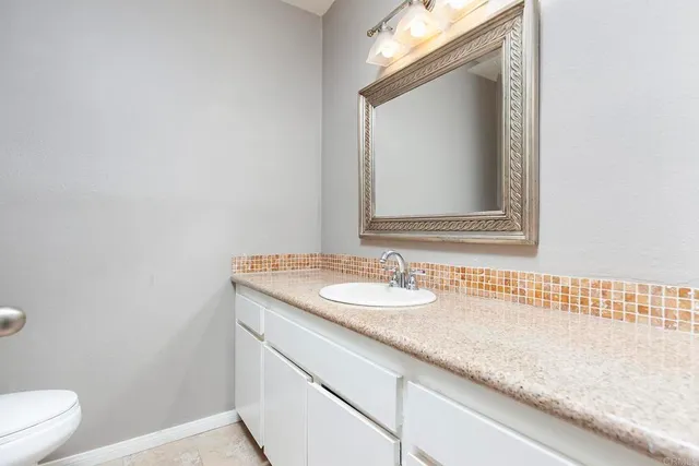 a bathroom with a granite countertop sink a toilet and a mirror