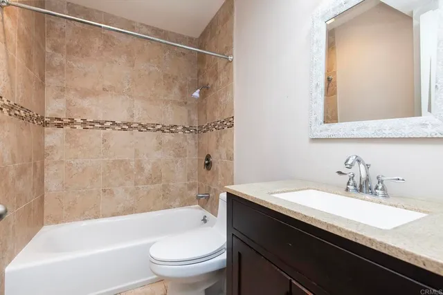 a bathroom with a granite countertop sink a toilet and shower
