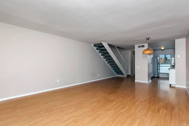 a view of an empty room with wooden floor stairs