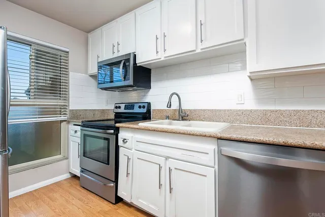 a kitchen with stainless steel appliances granite countertop a sink dishwasher a stove and a microwave oven with cabinets