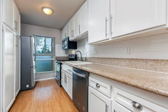 a kitchen with granite countertop a sink a counter space appliances and cabinets