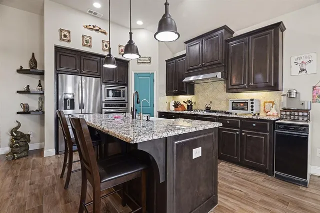 a kitchen with granite countertop wooden cabinets and stainless steel appliances