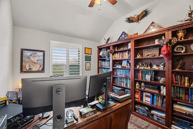 a view of a workspace with bookshelf and a window