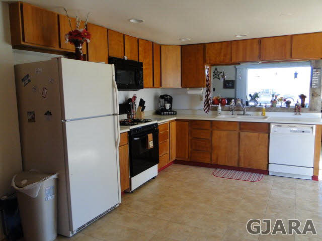 2335 J Road Grand Junction, CO 81505 - Photo 5 of 19 a kitchen with granite countertop a refrigerator a sink a stove and cabinets