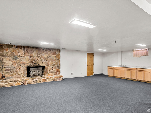 15680 North Beaver Dam Road Collinston, UT 84306 - Photo 28 of 49 Spacious room featuring a full stone fireplace, built-in wet bar with wood cabinetry and stone-look countertop, recessed ceiling lighting, and grey carpeting