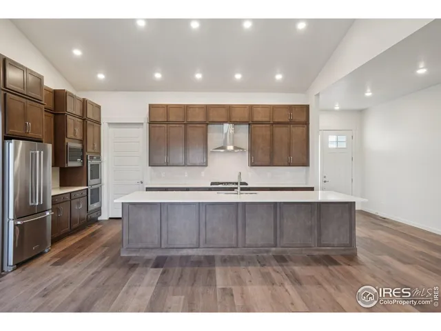 a view of kitchen with stainless steel appliances cabinets a sink and a wooden floor