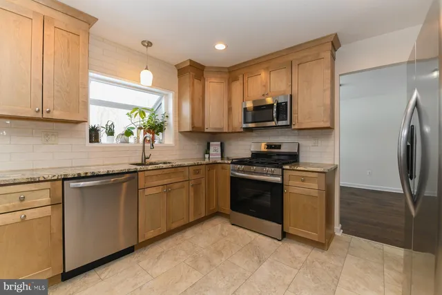 a kitchen with stainless steel appliances granite countertop a stove a sink and a refrigerator