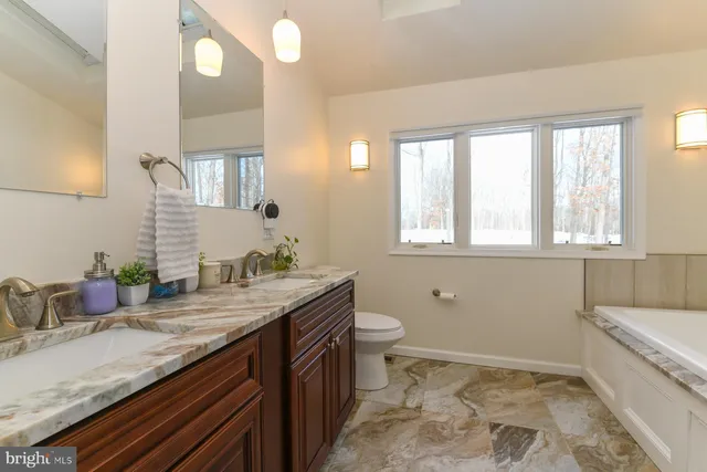a bathroom with a granite countertop sink a toilet and mirror
