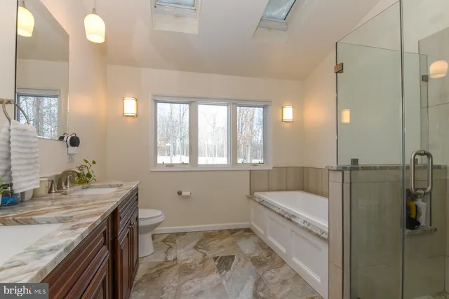 a bathroom with a granite countertop sink a toilet and bathtub