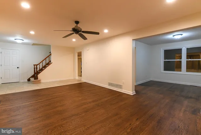 an empty room with wooden floor ceiling fan and windows