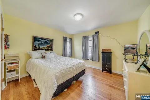 a bedroom with a bed a flat screen tv and dresser