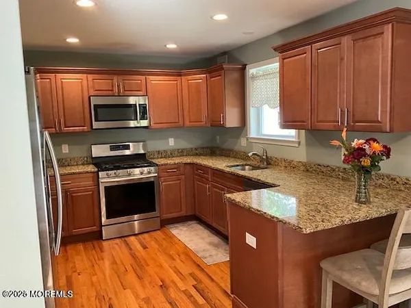 a kitchen with stainless steel appliances granite countertop a sink stove microwave and refrigerator