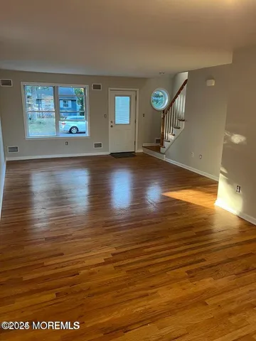a view of an empty room with window and wooden floor