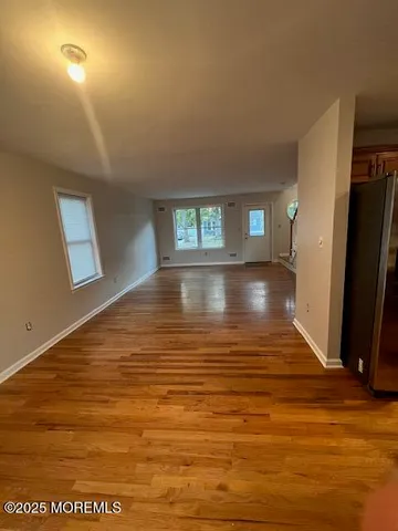 a view of empty room with window and wooden floor