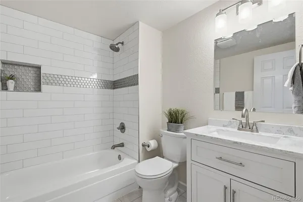 a bathroom with a bathtub shower sink vanity mirror and toilet