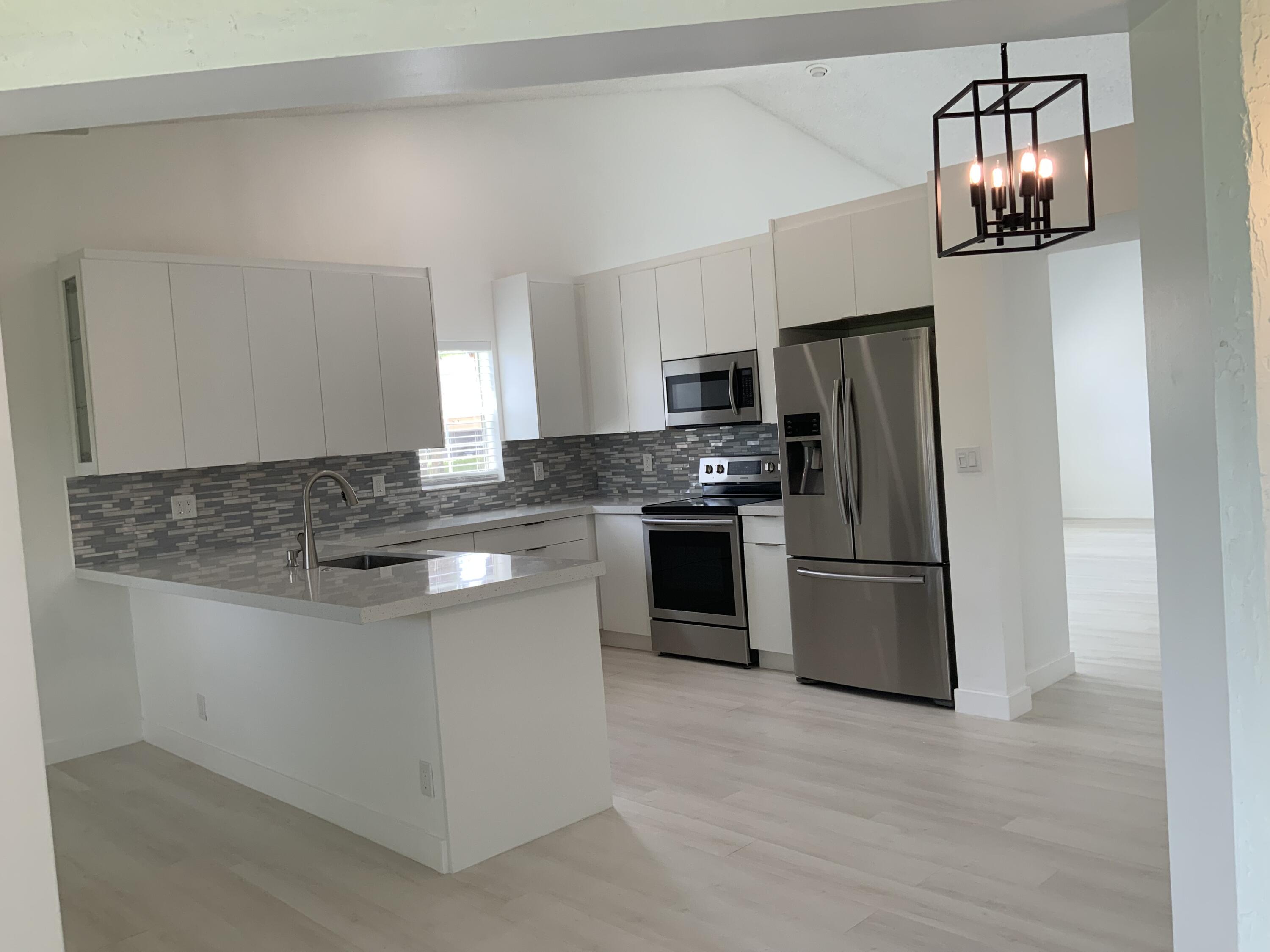 7591 Red Ruby Drive Delray Beach, FL 33446 - Photo 7 of 29 a kitchen with stainless steel appliances granite countertop a refrigerator and a stove top oven