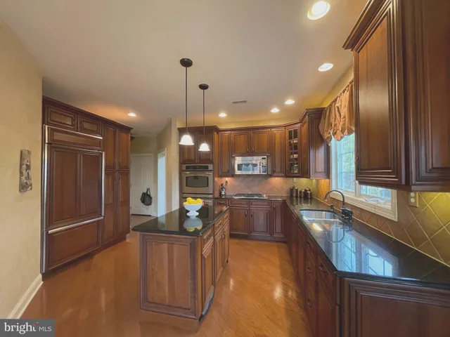 a kitchen with stainless steel appliances granite countertop sink stove refrigerator and cabinets