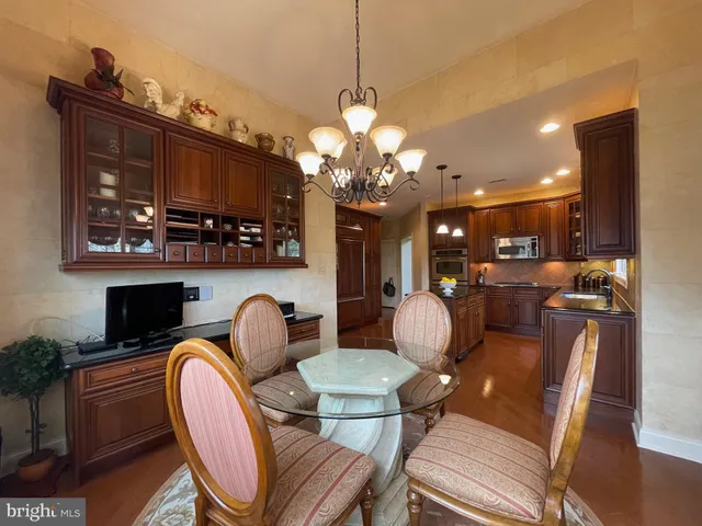 a dining room filled chandelier and wooden furniture