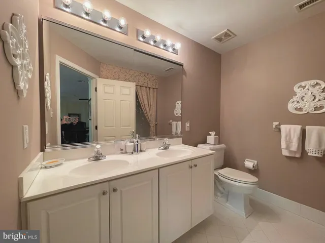 a bathroom with a double vanity sink toilet and a mirror