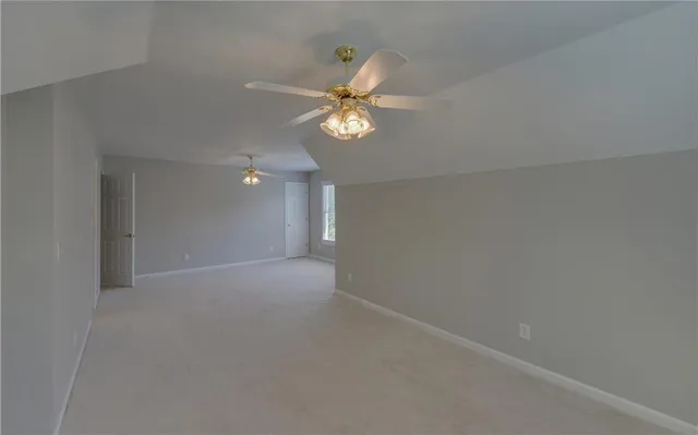 an empty room with a chandelier fan and a window