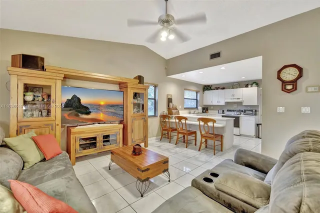 a living room with furniture kitchen view and a window