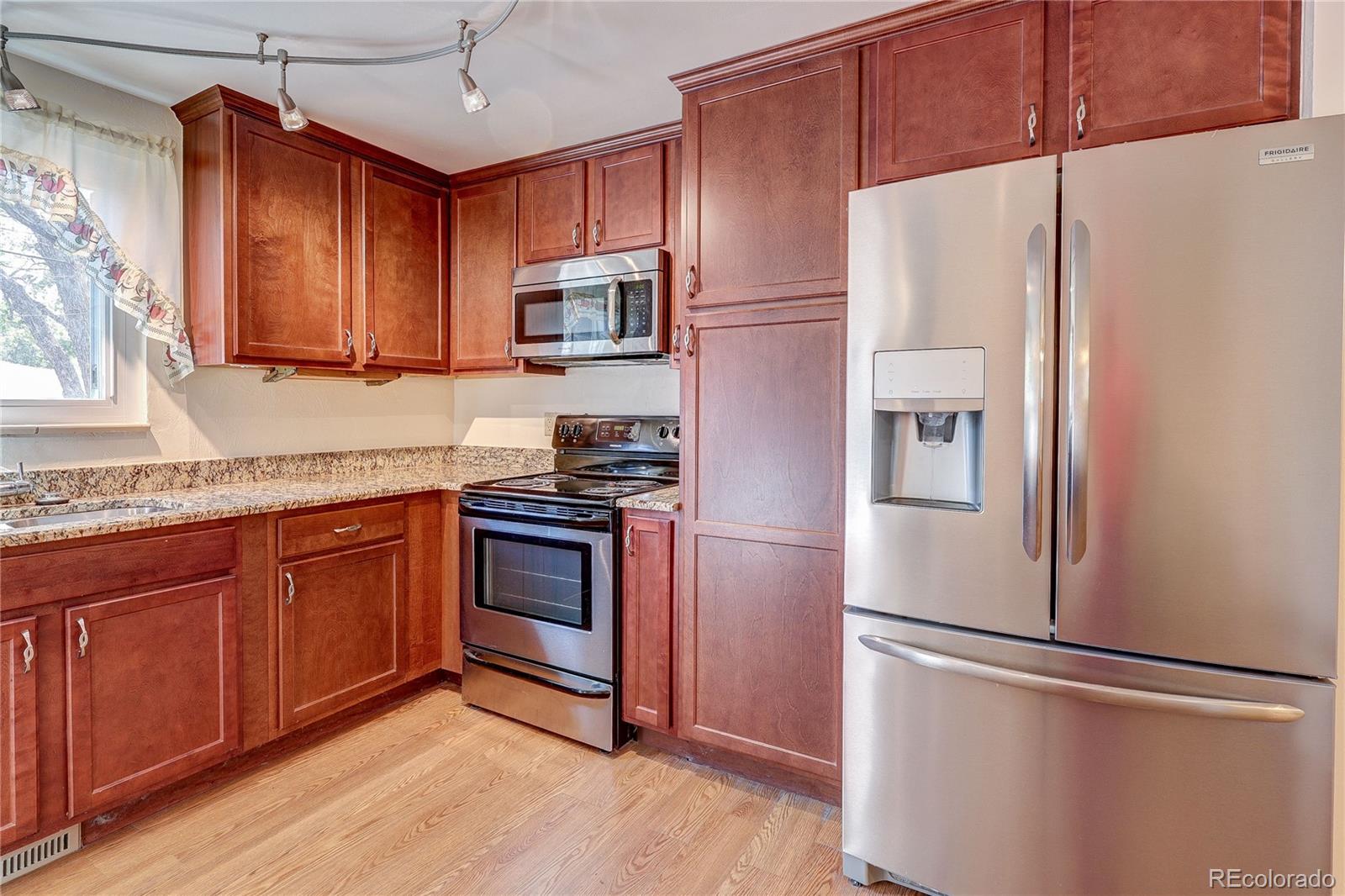 4570 Field Street Wheat Ridge, CO 80033 - Photo 14 of 44 a kitchen with stainless steel appliances granite countertop a refrigerator stove a sink and dishwasher with wooden cabinet