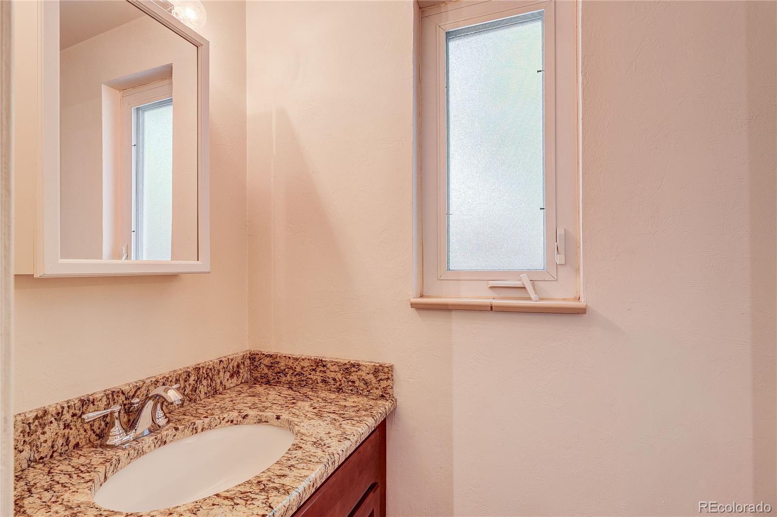 4570 Field Street Wheat Ridge, CO 80033 - Photo 24 of 44 a bathroom with a granite countertop sink and a mirror