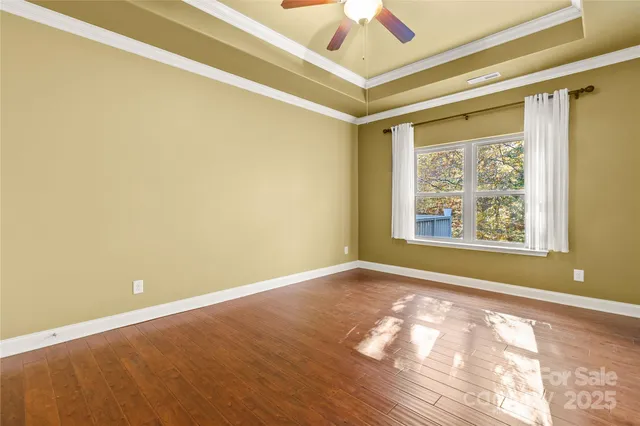 a view of an empty room with window and wooden floor