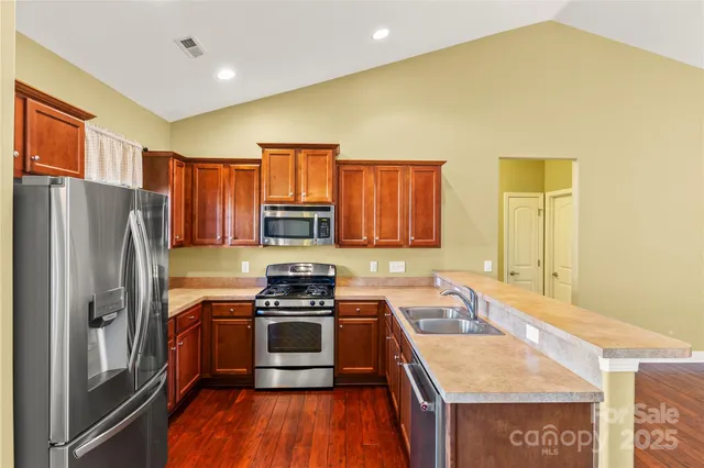 a kitchen with stainless steel appliances granite countertop a stove a sink and a microwave