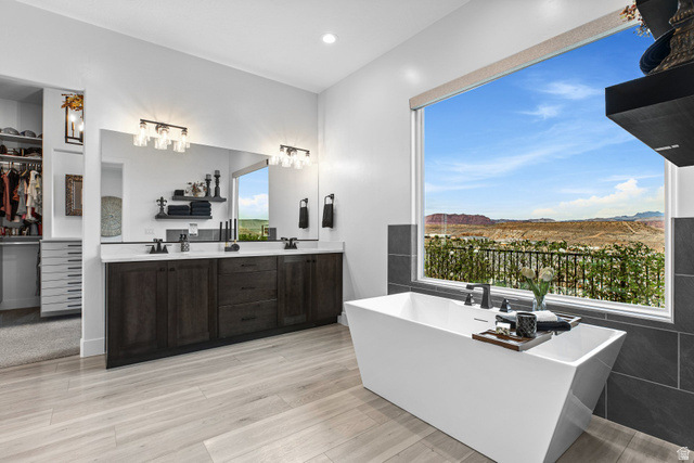3022 West Sesia Way St. George, UT 84770 - Photo 25 of 52 Bathroom featuring a walk in closet, double vanity, a soaking tub, light wood-style flooring, and a mountain view