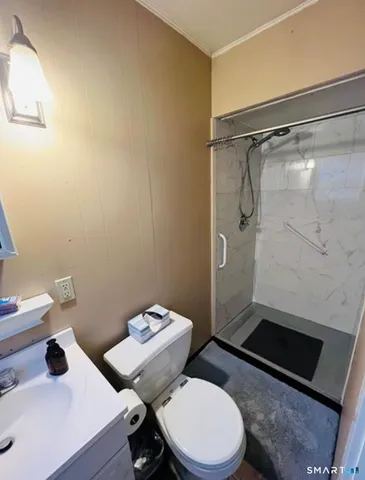 a white toilet sitting next to a bathroom sink and a shower