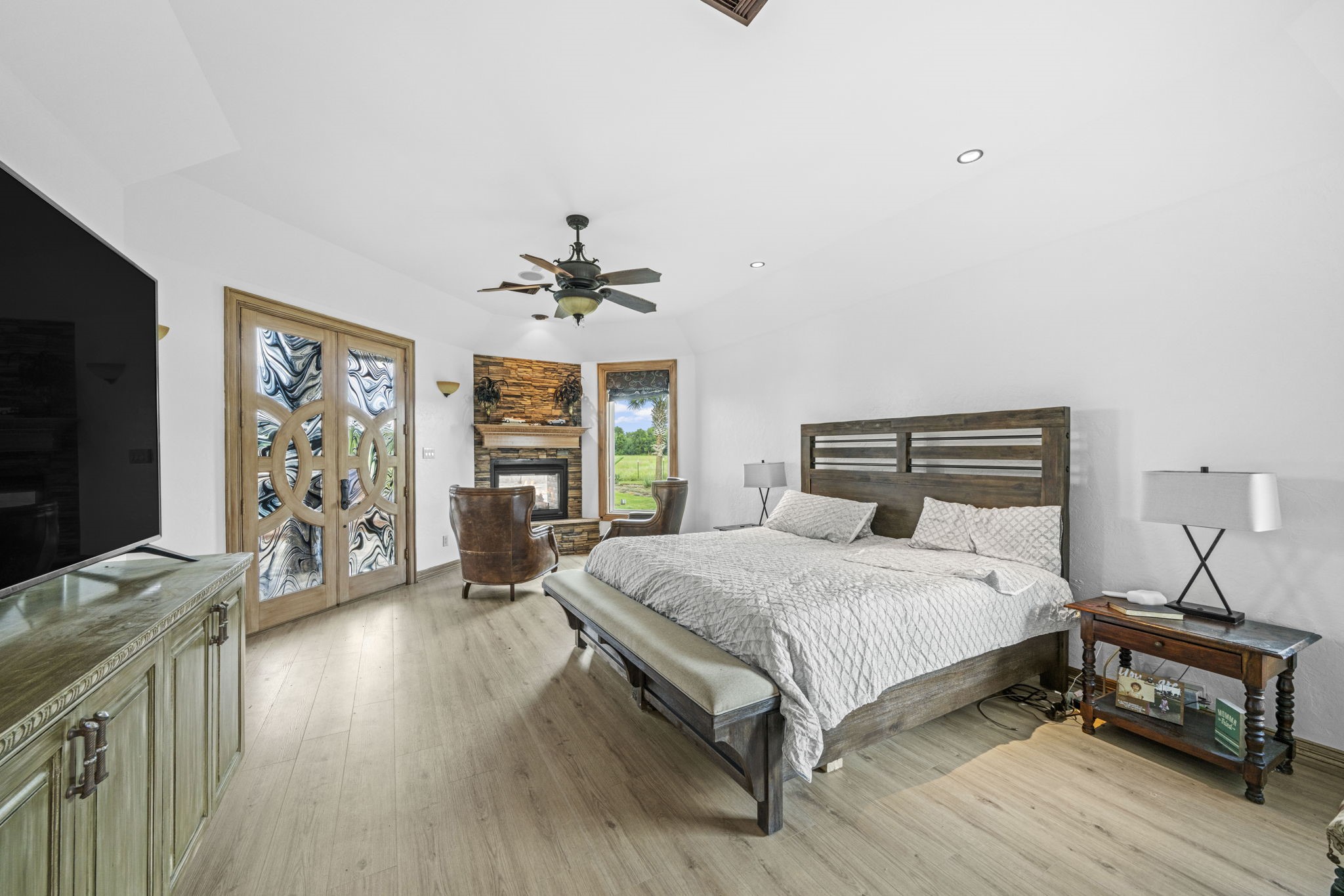 18732 Kz Road Cypress, TX 77433 - Photo 25 of 49 Wake up to paradise in a primary suite boasting a stunning indoor-outdoor fireplace and large custom double doors that extend your space onto the covered patio.