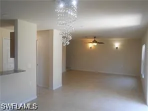 en empty room with chandelier fan and window