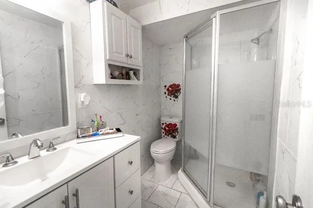 a bathroom with a granite countertop sink a toilet and shower
