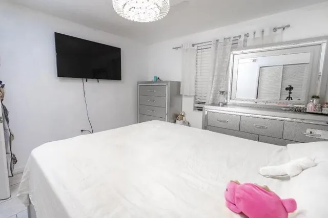 a spacious bedroom with a bed and a flat screen tv