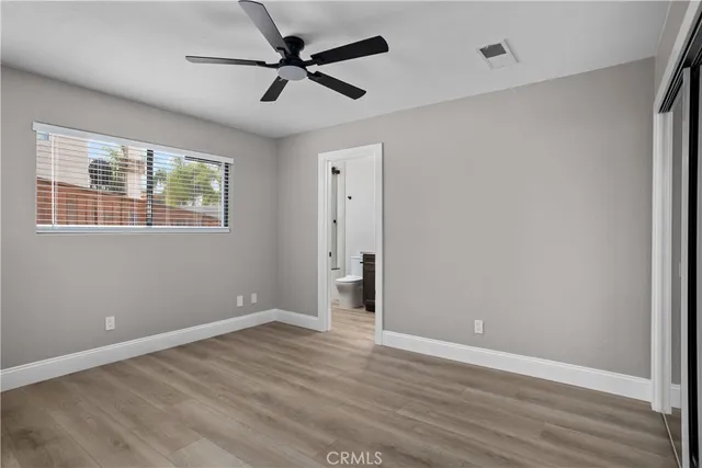 an empty room with wooden floor fan and windows
