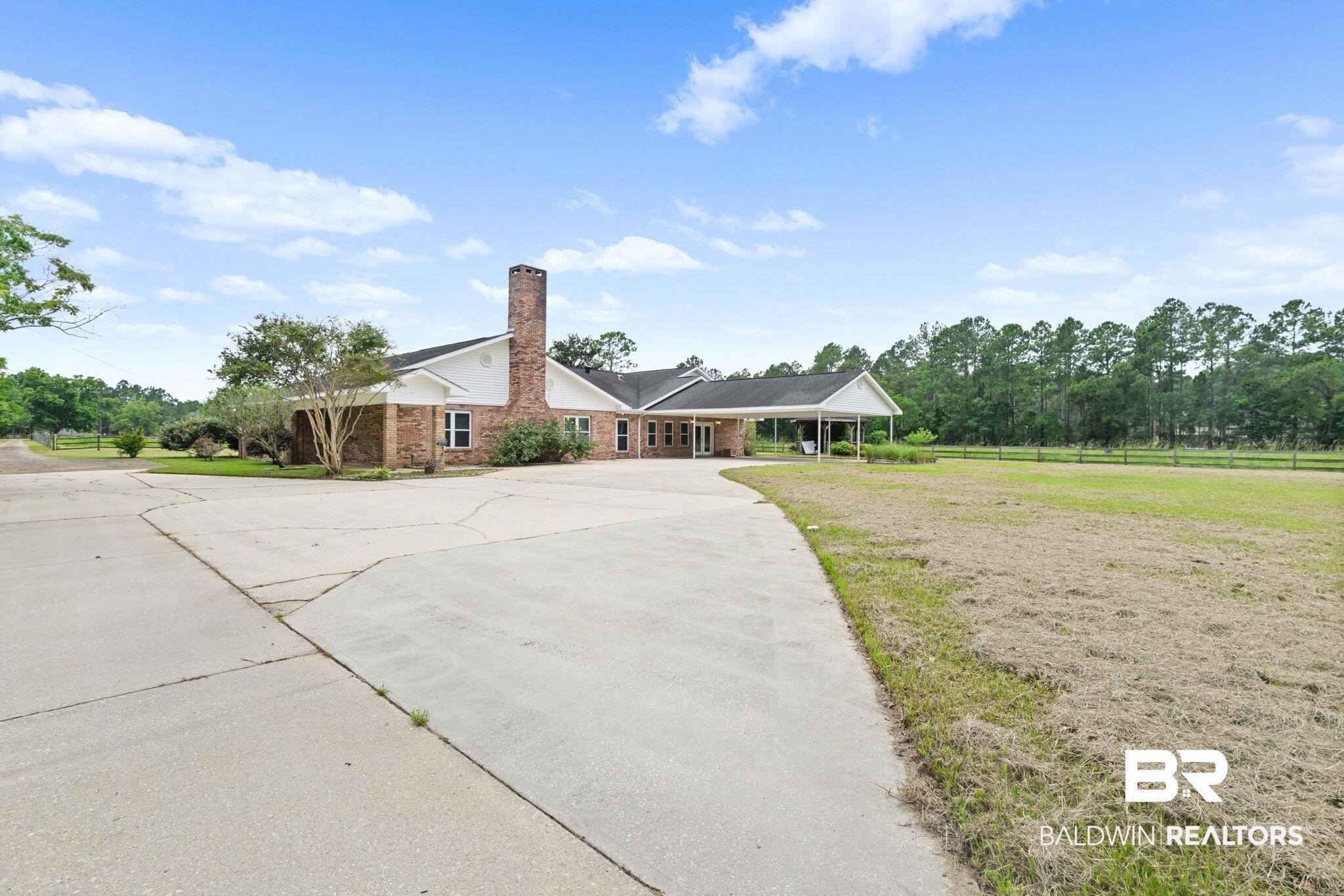 7540 2 Mile Road Irvington, AL 36544 - Photo 2 of 82 Brick exterior residence with a prominent chimney, large paved driveway, and covered carport