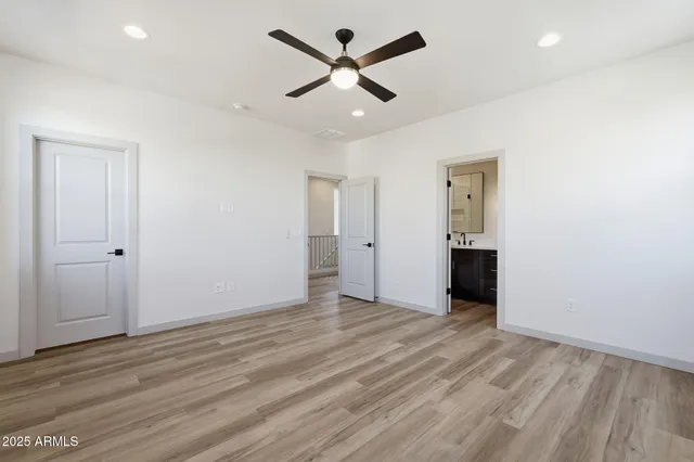 an empty room with wooden floor and ceiling fan