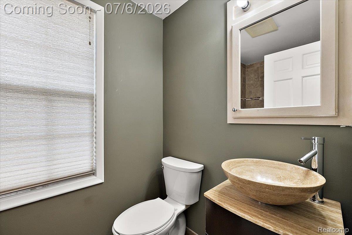 1051 Devonshire Road Grosse Pointe, MI 48230 - Photo 51 of 98 Powder room featuring a stone vessel sink, chrome faucet, wood-finish vanity countertop, and wall-mounted medicine cabinet with integrated lighting