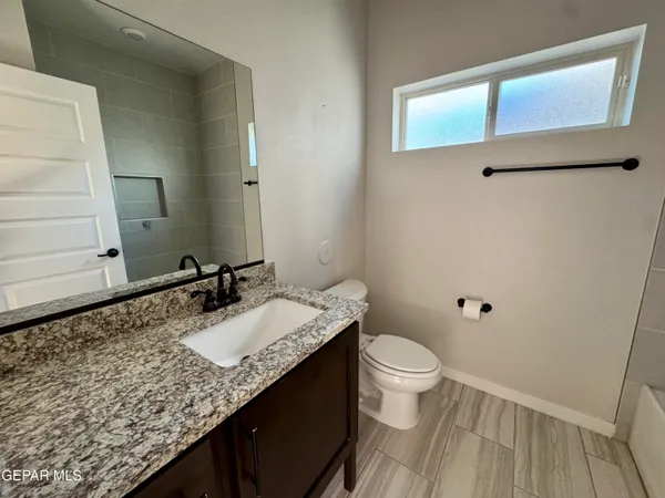a bathroom with a granite countertop sink a toilet and a mirror